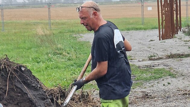Håkan fyller skottkärran i regn för att fylla igen stolphål.